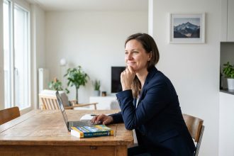 Femme en blazer assise à la cuisine avec guide voyage Suisse